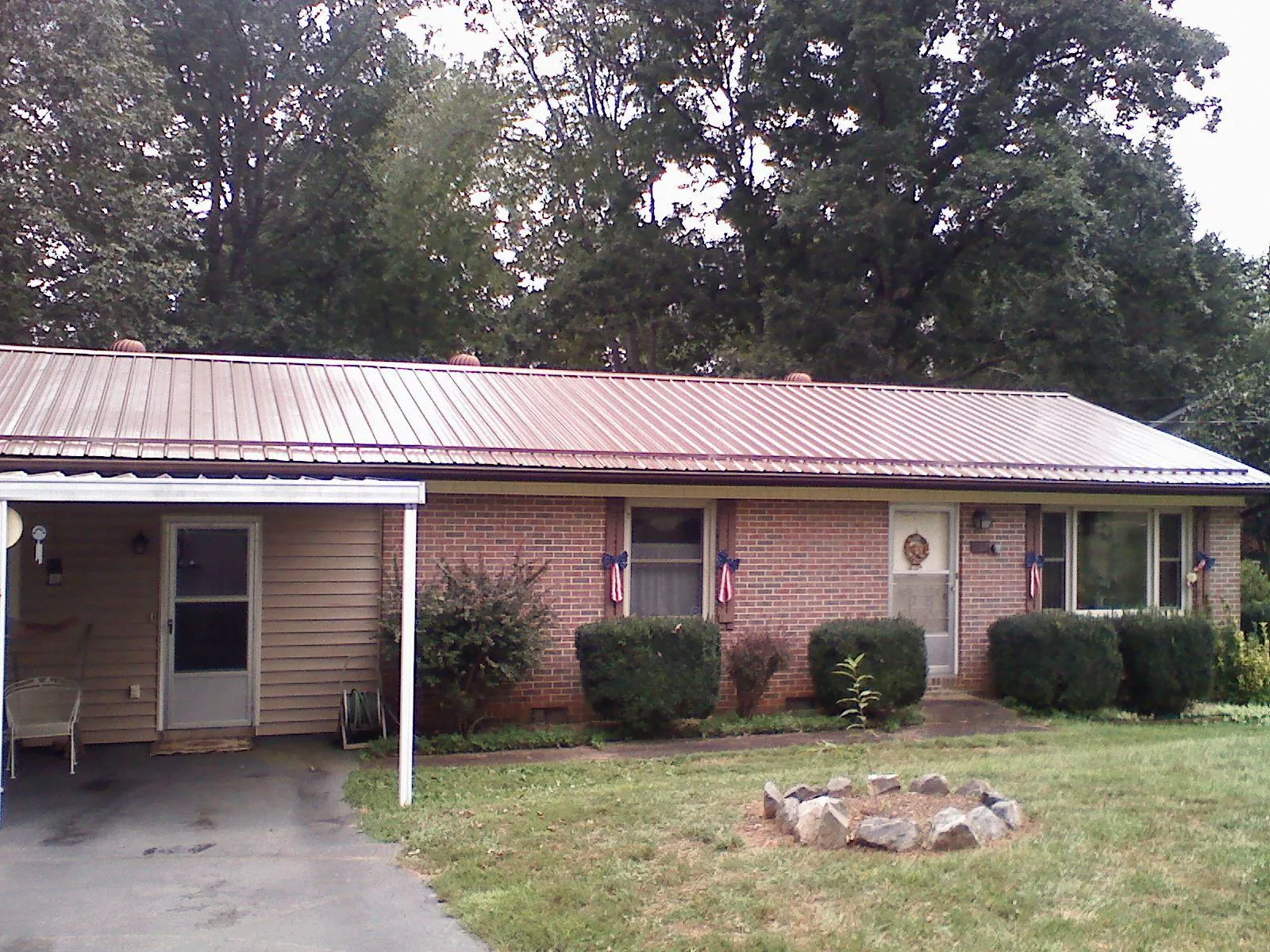 Bronze metal roof and carport on a brick ranch home — Roof Repair work by our crew in Mead